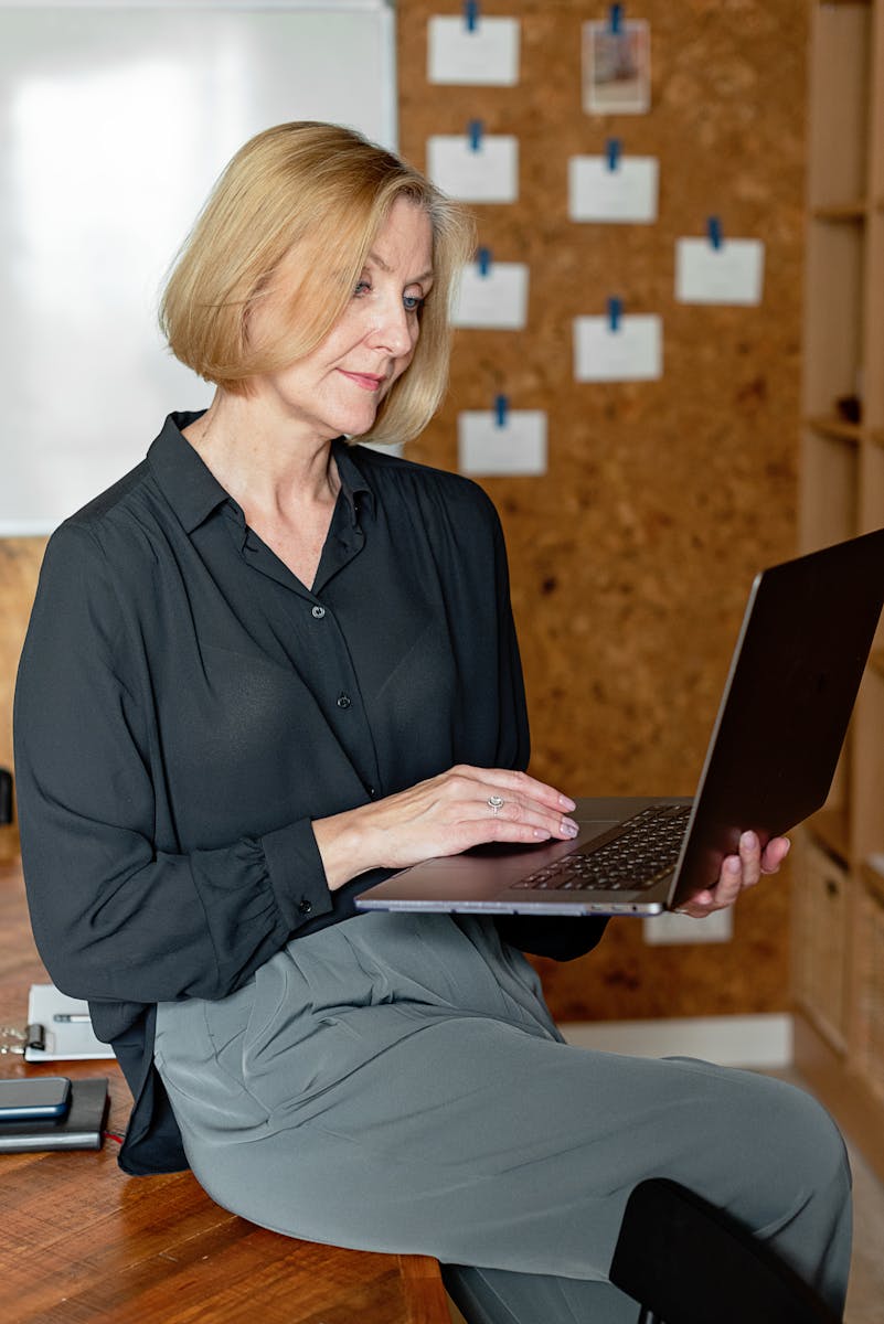 Senior woman in office setting using a laptop for work, showcasing productivity.
